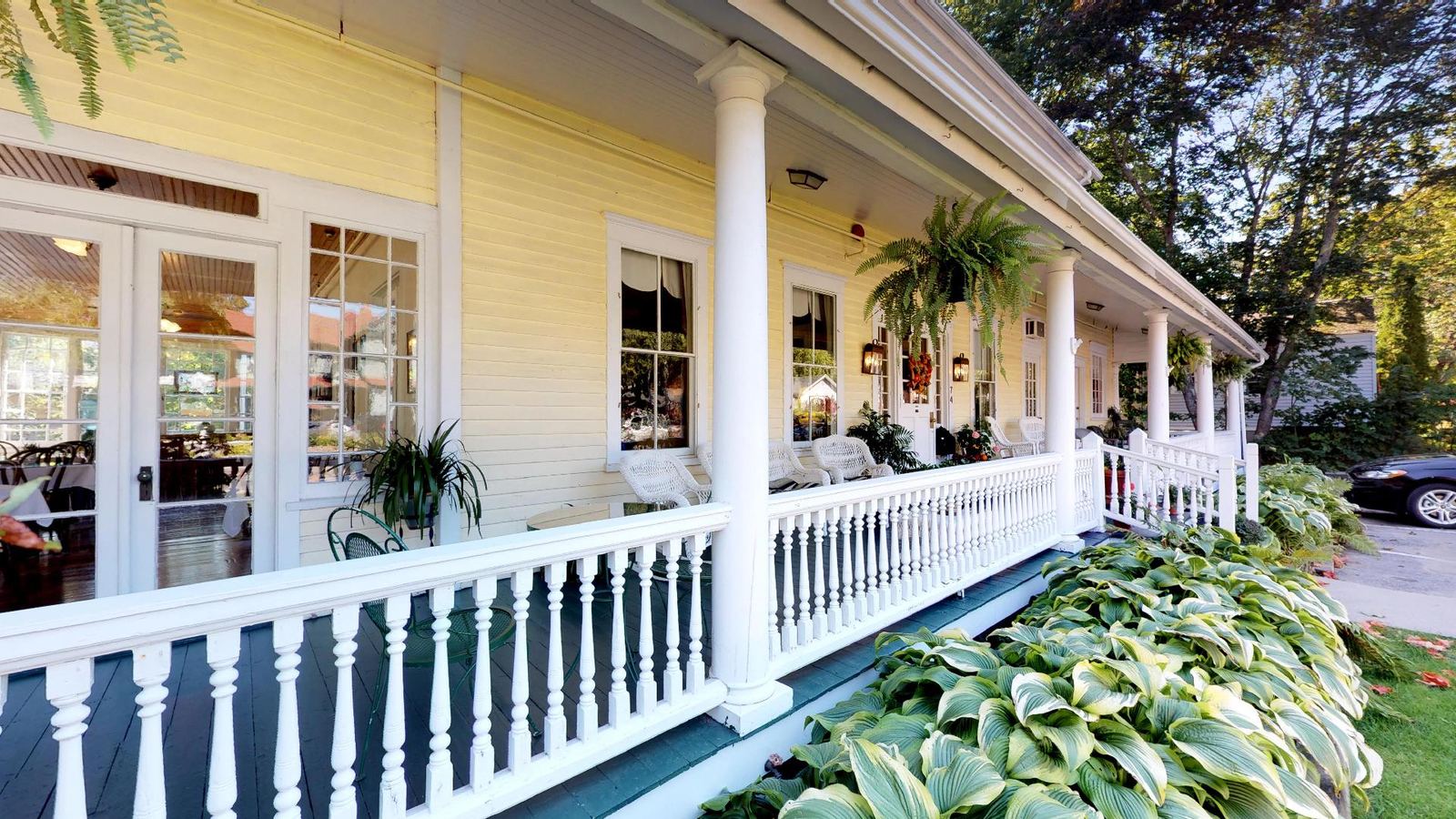 Yellow Victorian front porch with white railings and wicker chairs